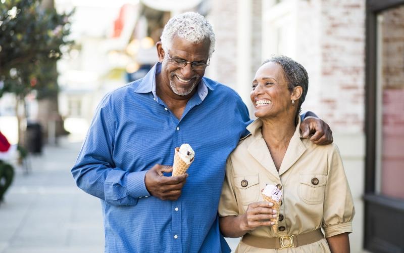 older couple walks down city sidewalk while holding ice cream cones